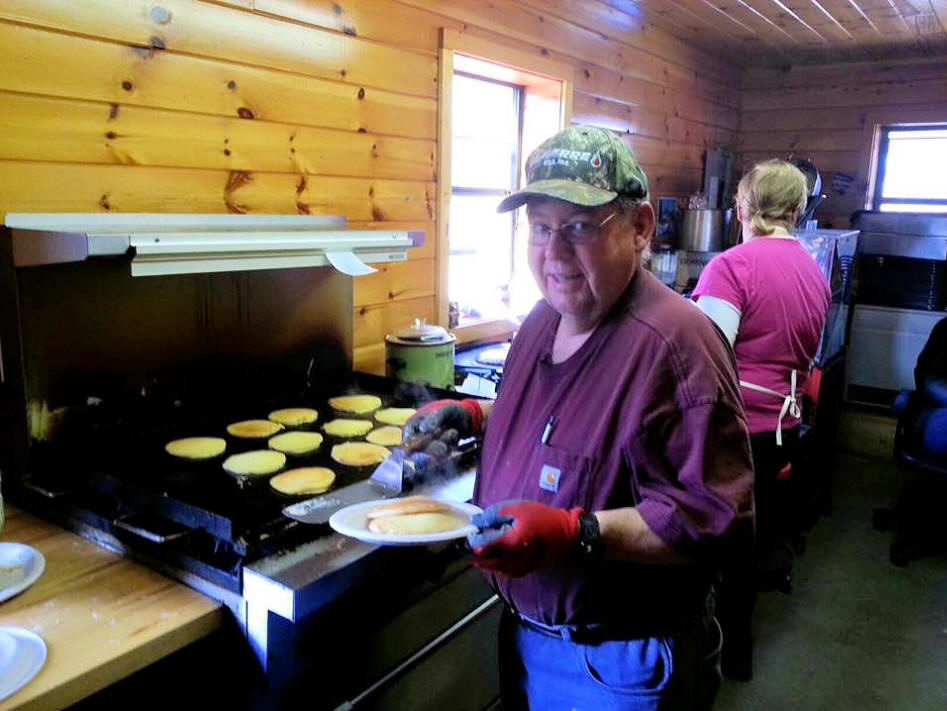 man serves himslef some pancakers from griddle in cabin in the Adirondacks