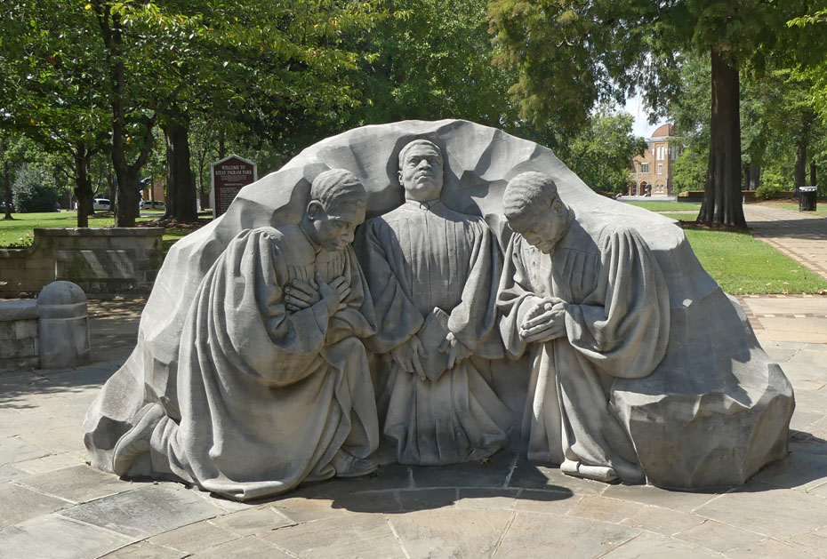Sculpture in Kelly Ingram P{ark showing 3  preachers praying