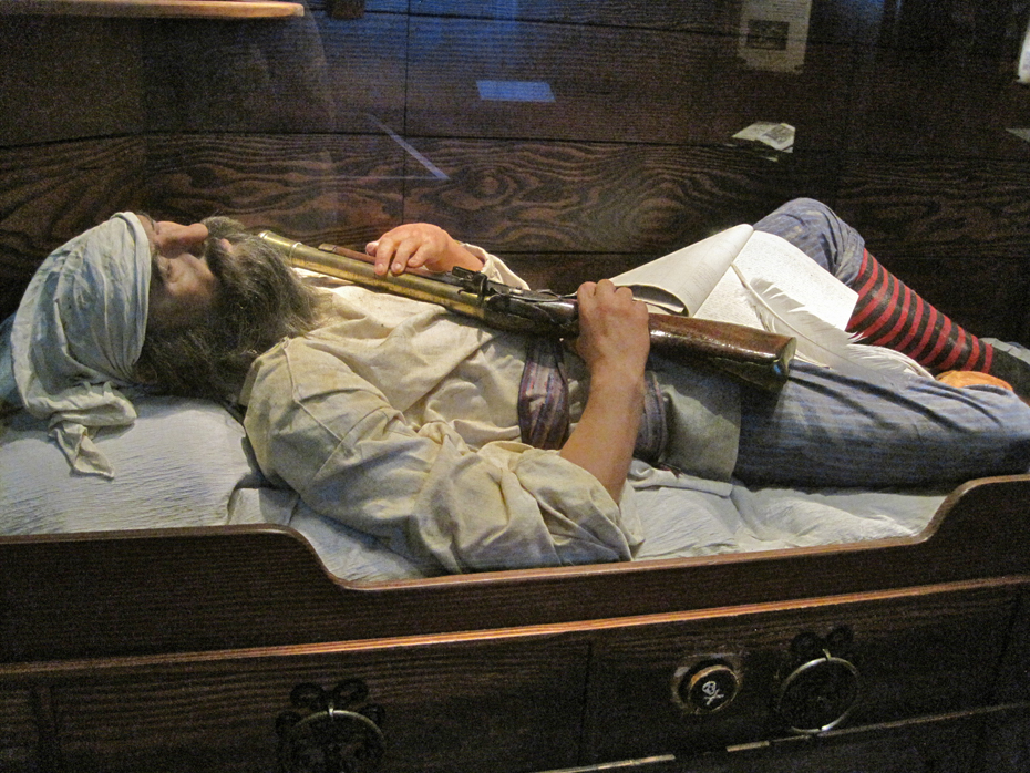 :pirate" sleeps in hsi bunk with musket at the St. Augustine Pirate and Treasure Museum