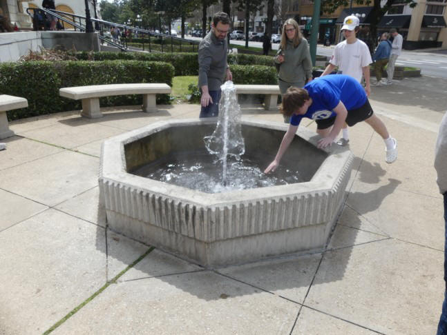 boy dipping his hand  in hot springs fountain