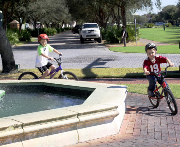 Two little boys riding bikes at fountain in Rosemary Beach, florida