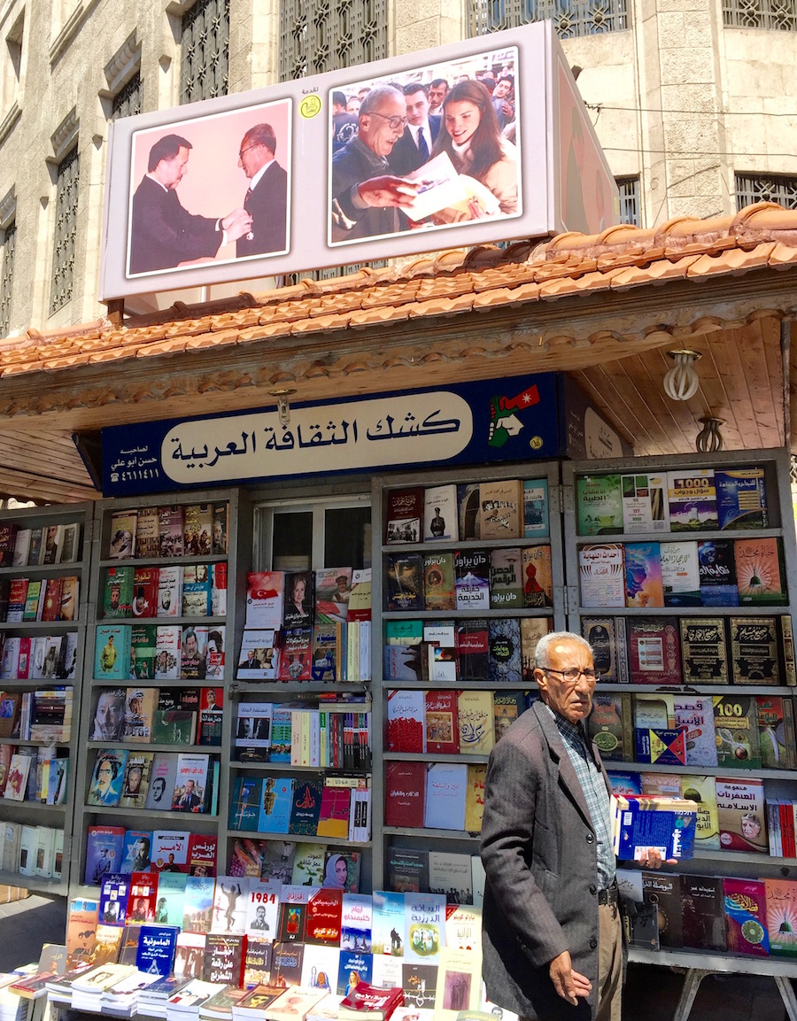 street bookstore in Amman with owner in front. Picture of King and Queen shoping there above