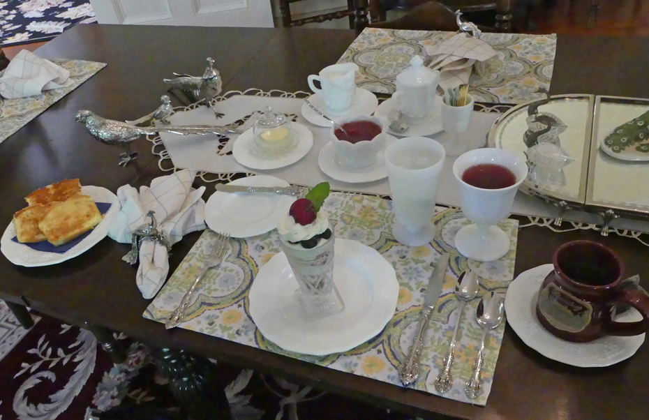 breakfast table set with white china and bread and strawberry soup