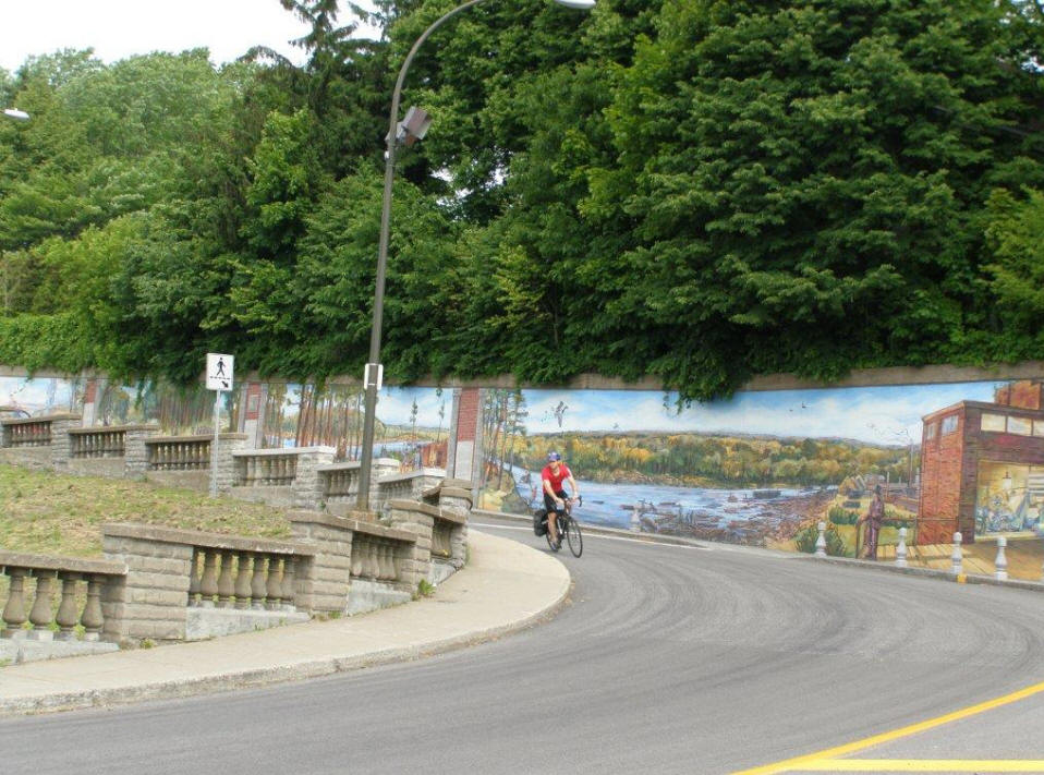 La Fresque de Trois Rivieres (fresco) with biker in front on roadway.