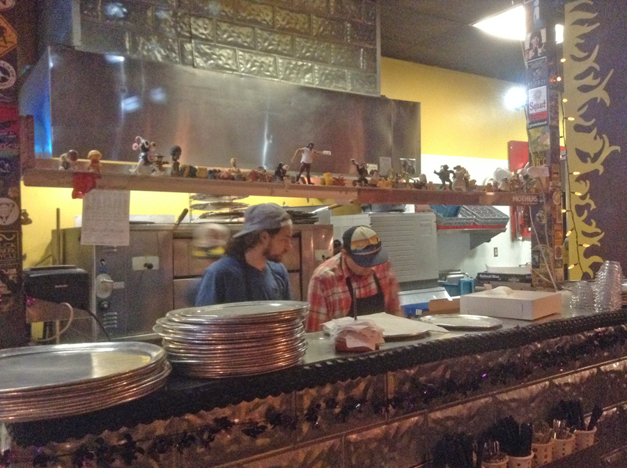 Workers behind the counter preparing pizza at Lupi’s Pizza in Chattanooga