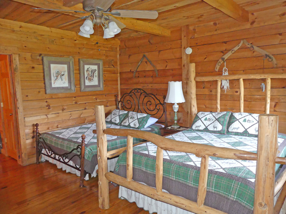 bedroom wiht two beds one rustic logs at French Broad Outpost Dude Ranch in Eastern Tennessee