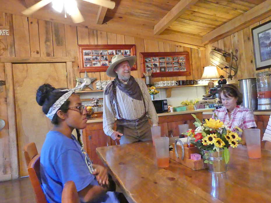 Man in cowboyoutfit with two women at table at French Broad Outpost Dude Ranch in Eastern Tennessee