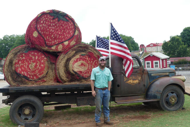 man in front of truck wiith haybales