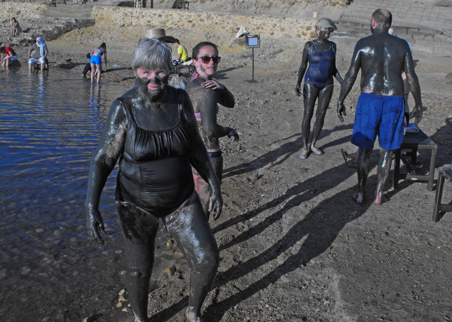 People covered with mud on the banks of  Dead sea